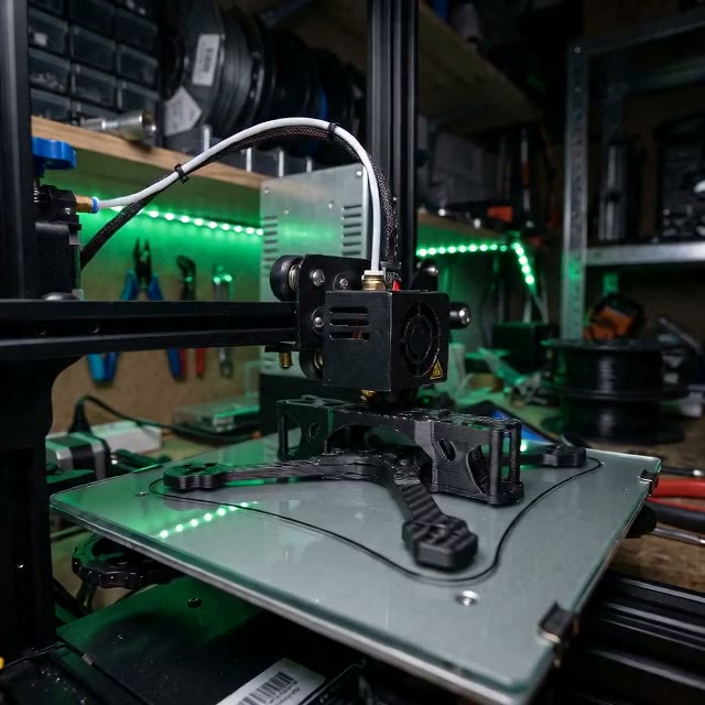 Карбонова деталь дрона на 3D-принтері під зеленим підсвітленням